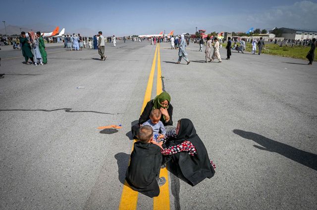 Afghans on the tarmac while waiting in Kabul on August 16, 2021