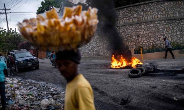 A street vendor passes through a burning tire barrier during a demonstration against price hikes and fuel shortages in Port-au-Prince, Haiti. Photo: Ricardo Arduingo/AFP