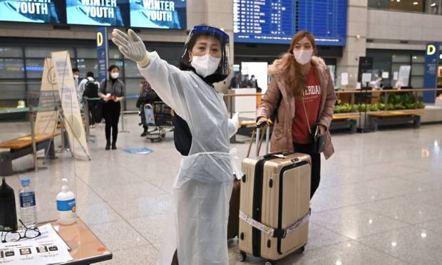Amid growing concerns about the Ômicron variant of the Covit-19, an airport official guides passengers at the arrival hall of Incheon International Airport in South Korea Photo: JUNG YEON-JE / AFP