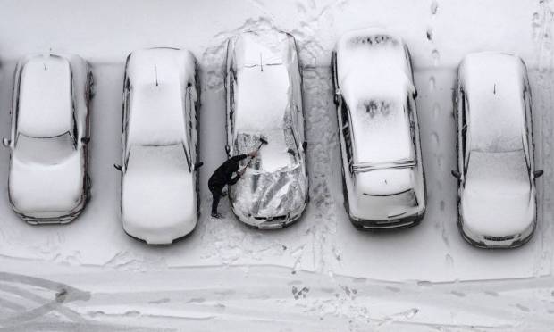 Photo of a man wiping snow in a car in Moscow: Natalia Kolesnikova / AFP