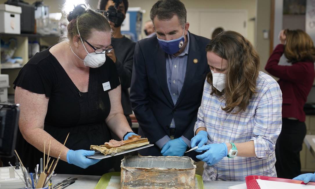 Governor Ralph Northam, center, watching as chief conservator of the Virginia Department of Historical Resources, Kate Ridgway, left, and Sue Donovan, University of Virginia Special Collections keeper, right, remove the contents of the time capsule.: Steve Helber/AP