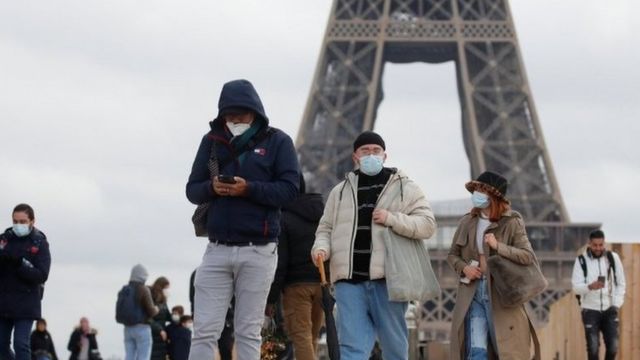 People wearing masks walk in Trocadero Square near the Eiffel Tower in Paris.