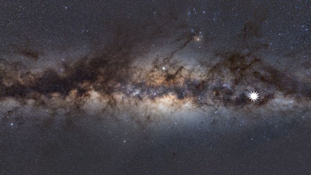 Imagem mostra a Via Láctea vista desde a Terra, com um ícone de estrela para identificar a posição do objeto enigmático