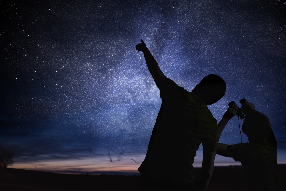 The picture shows two human photographs observing the starry sky with a telescope.