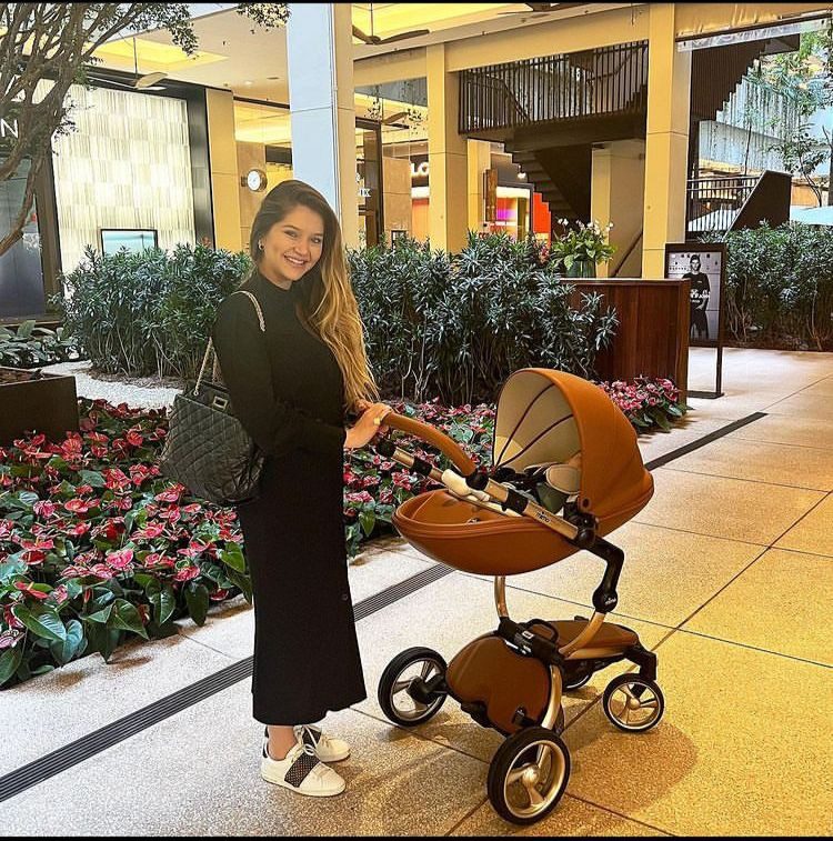 Leandro's daughter stands with her son in a luxury pram
