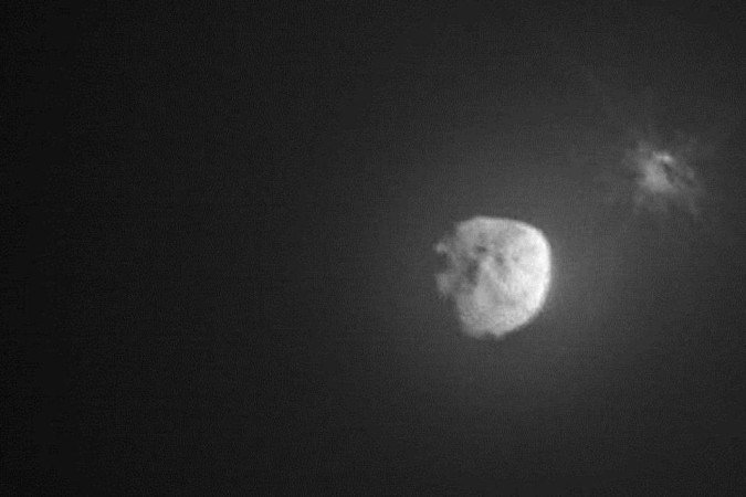 Na imagem, é possível ver o asteroide maior, Dídimos, e, Dimorphos, o objeto menor à direita e alvo da missão. É possível ver rastros de luz em volta da rocha, causada pelo impacto com a nave Dart -  (crédito: ASI/NASA)